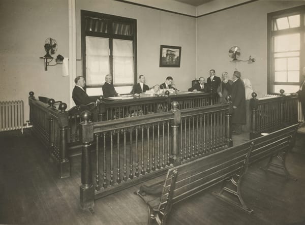 A bearded immigrant appearing before a board of inquiry
