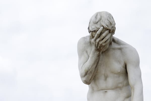 Statue of a man showing disappointment under a cloudless sky